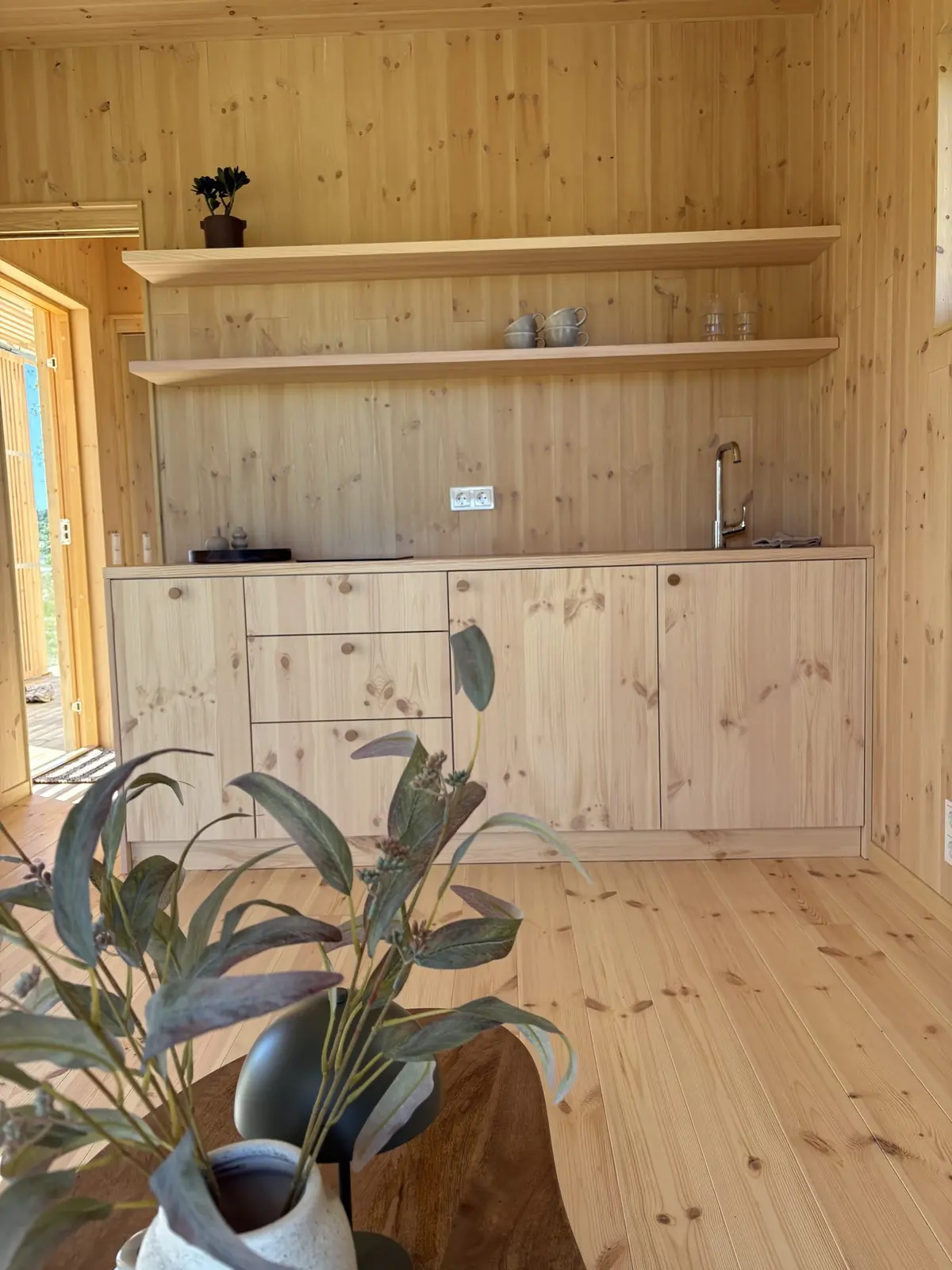 Köket i visningshuset, i ljust trä med öppna hyllor