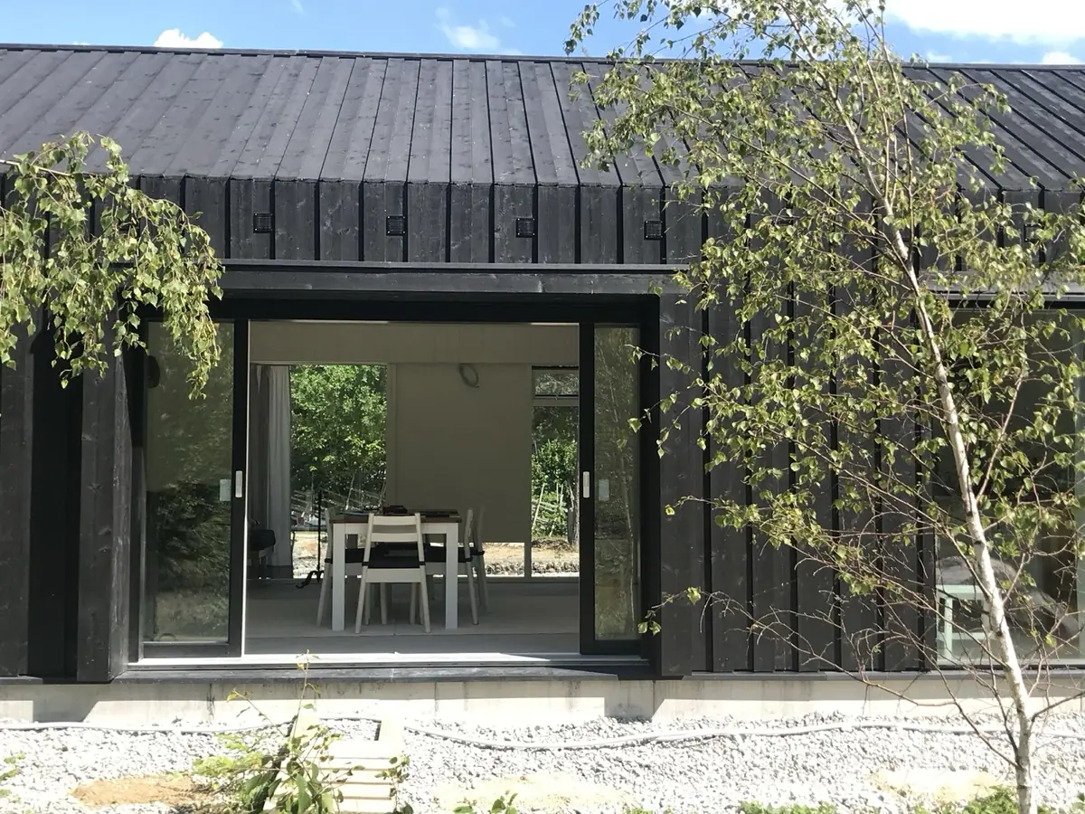 Specialritat hus i svart trä med stora skjutpartier mot altanen